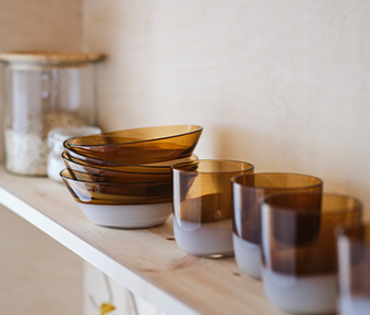 Calcetines navideños con diseño de cuadros verdes y rojos colgados de perchas de madera. Al lado, una corona de abeto con piñas.