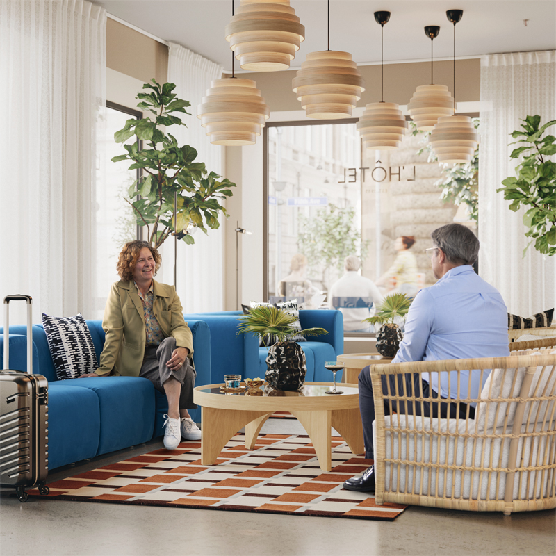 Outdoor area outside a hotel lobby with dark blue SUNDSÖ tables and chairs with a person reading whilst enjoying coffee.