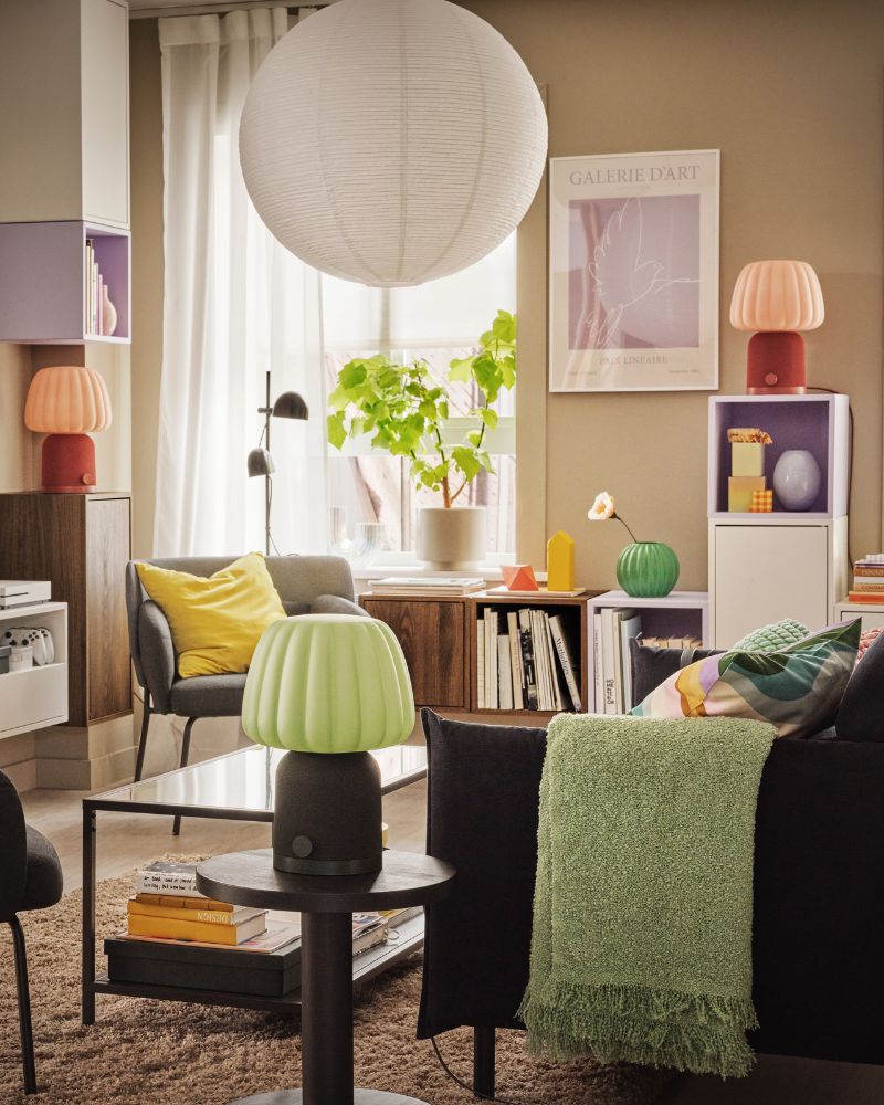 A light, colourful living room with plants, decoration and three KULGLASS Bluetooth speaker lamps scattered across the room.