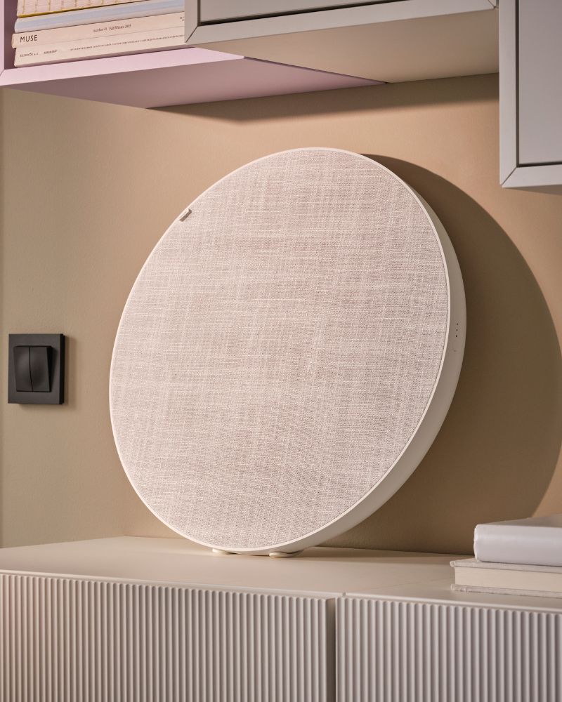 A white SOLSKYDD Bluetooth speaker placed on BESTÅ cabinets, leaning against the wall beneath a combo of EKET cabinets.
