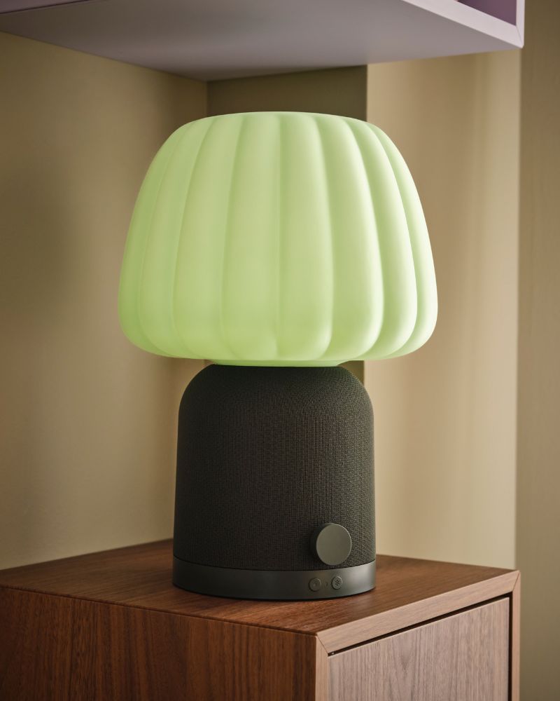 A dark-green KULGLASS Bluetooth speaker lamp placed in the space between two EKET cabinets, one mounted over the other.