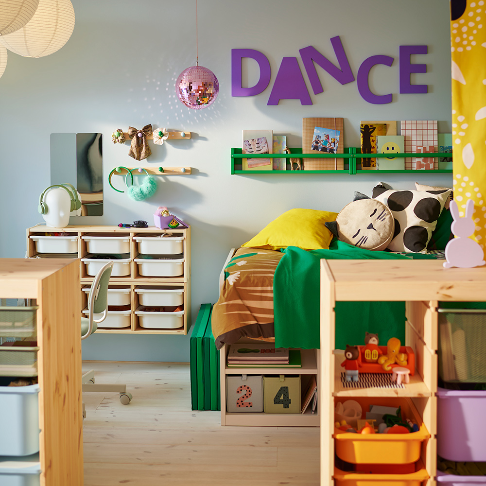 Un lado de un dormitorio infantil compartido, dividido por un separador TROFAST, que muestra una cama SLÄKT y un almacenaje de pared FLISAT.