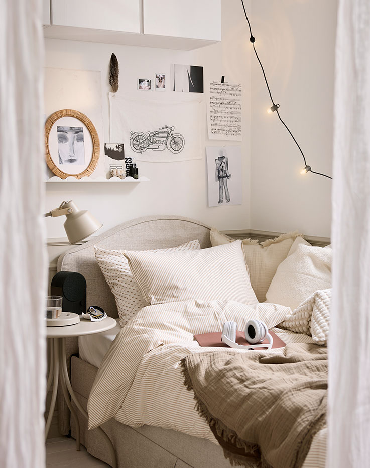 A bedroom scene with a white beige SOLFIBBLA duvet cover and pillowcase set neatly on a bed with striped neutral bedding.