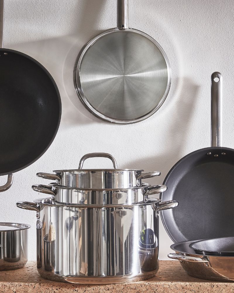 Set of frying pans and pots from the IKEA 365+ range in different sizes, made of stainless steel and neatly arranged.