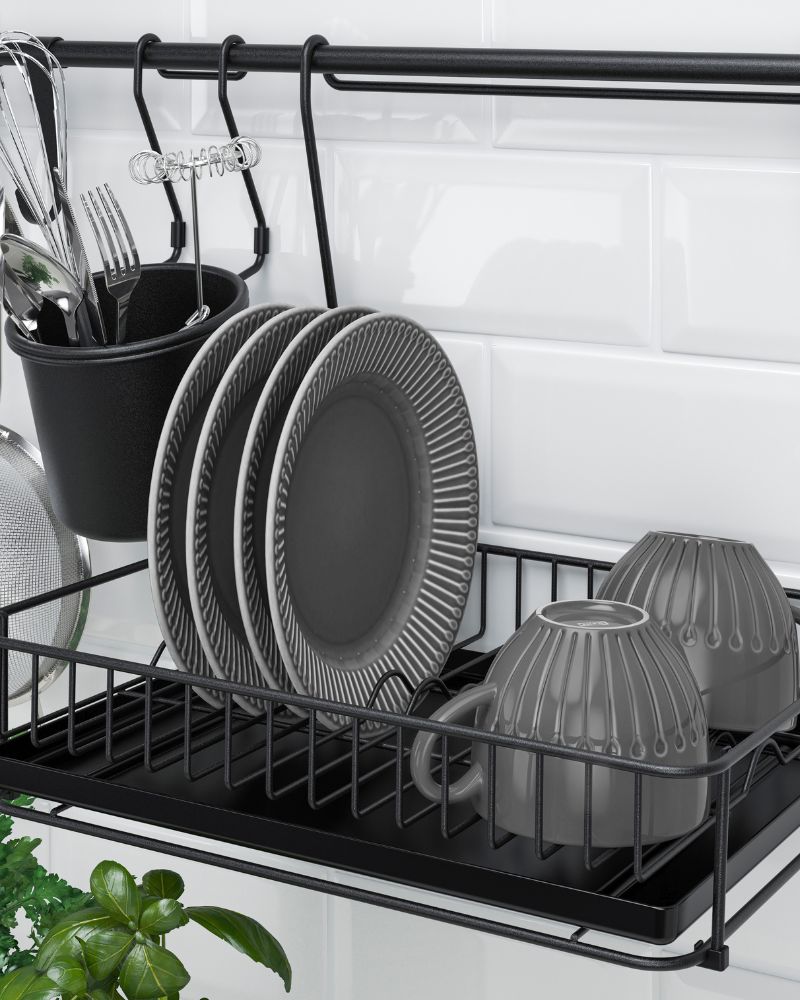 Dish rack HULTARP with IKEA 365+ cutlery, plates, cups, strainer and whisk on a black metal rack with hooks and drip tray.
