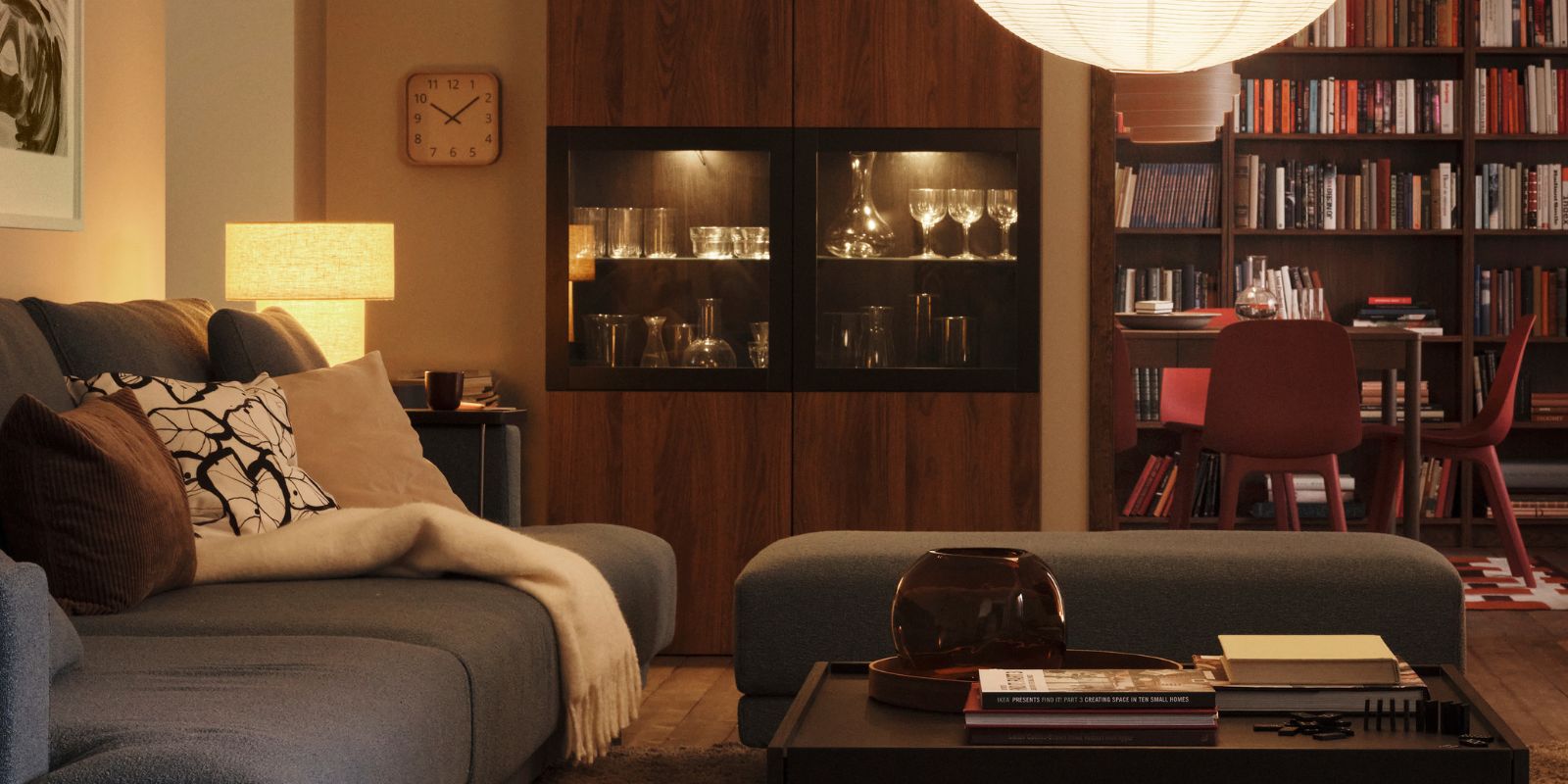 A lamp with a GULLSUDARE pendant lampshade hangs in a living room with a STOCKHOLM 2025 table lamp in one corner.