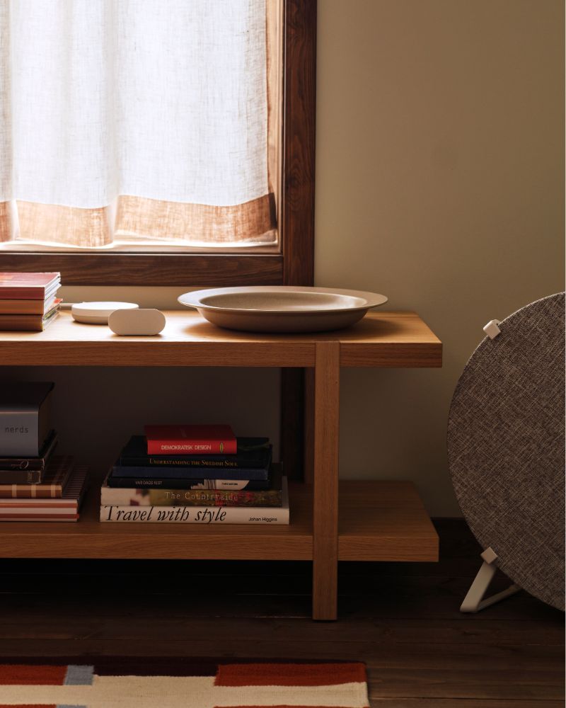 An ALPSTUGA air quality sensor sits on top of a STOCKHOLM 2025 shelving unit/bench standing next to a STARKVIND air purifier.