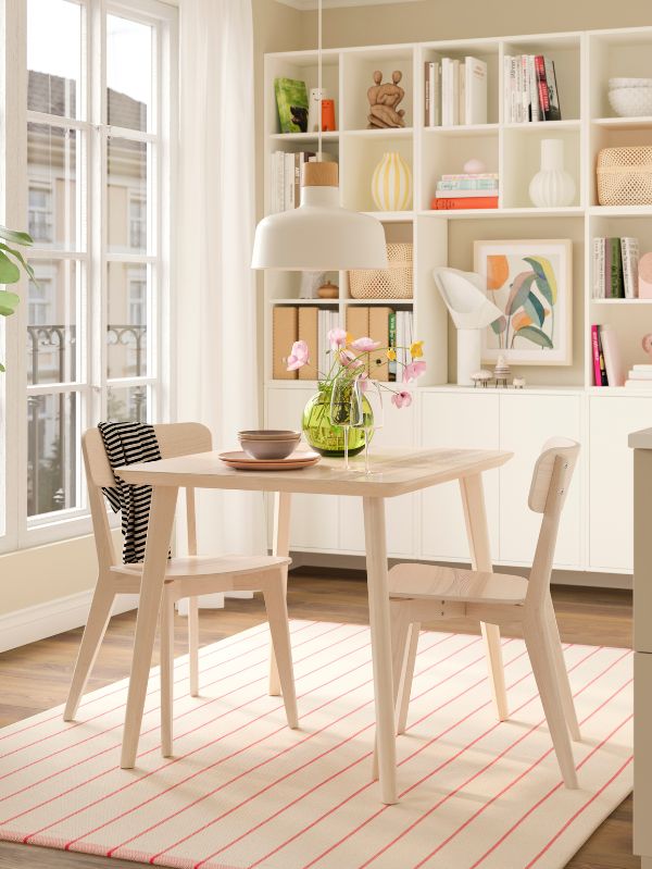 Soft dining area with LISABO table set, BUNKEFLO lamp, RIDSTIG rug, EKET shelving and BLODBJÖRK and FRÖVÄXT vases.