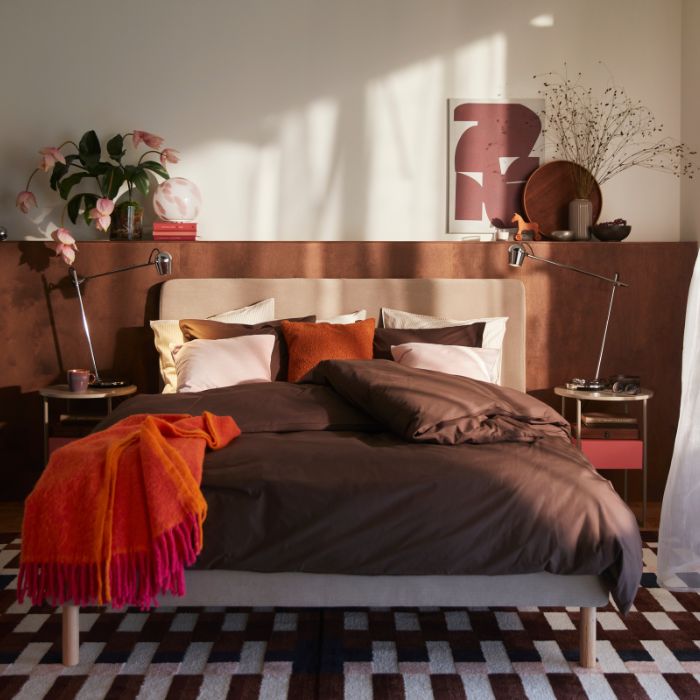 A cosy bedroom featuring a TÄRNKULLEN upholstered bed frame with a brown HAMPFLOCKEL duvet cover and 2 pillowcases.