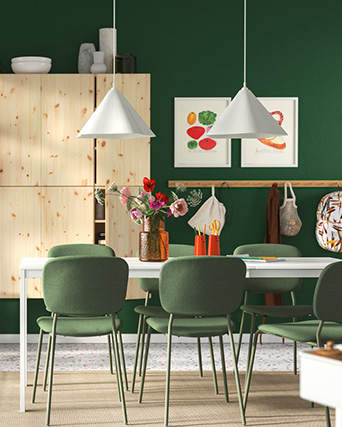Dining room with green wall, matching chairs, white table, conical lamps, and a light wood sideboard.