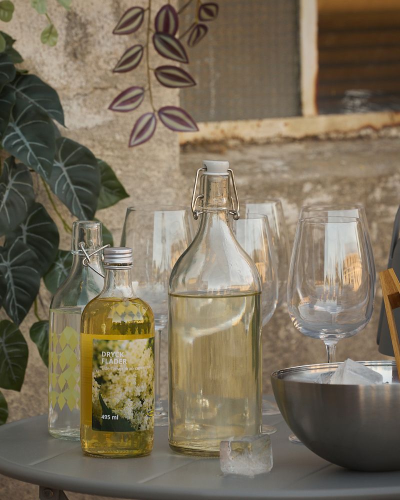 Cozy terrace with STORSINT glasses, KORKEN bottles and BLANDA BLANK bowls for stylish outdoor serving.