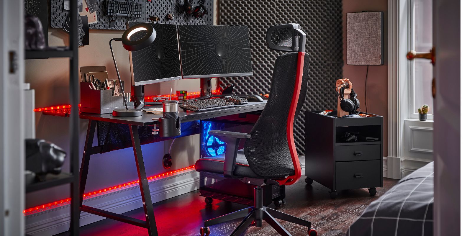 A neon‑lit gaming room with the UTVISNING desk and LÖPARBANA chair, enhanced by the LÅNESPELARE ring light for a vibrant setup.