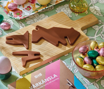 Chocolate pieces shaped like a bunny figure placed on a wooden board, surrounded by colorful Easter eggs.