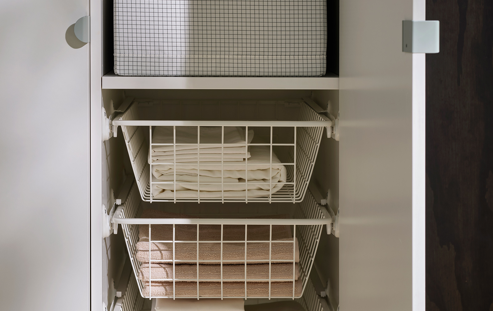 Inside a LASTARE wardrobe combination with STUK boxes on shelves and wire baskets storing neatly folded textiles.
