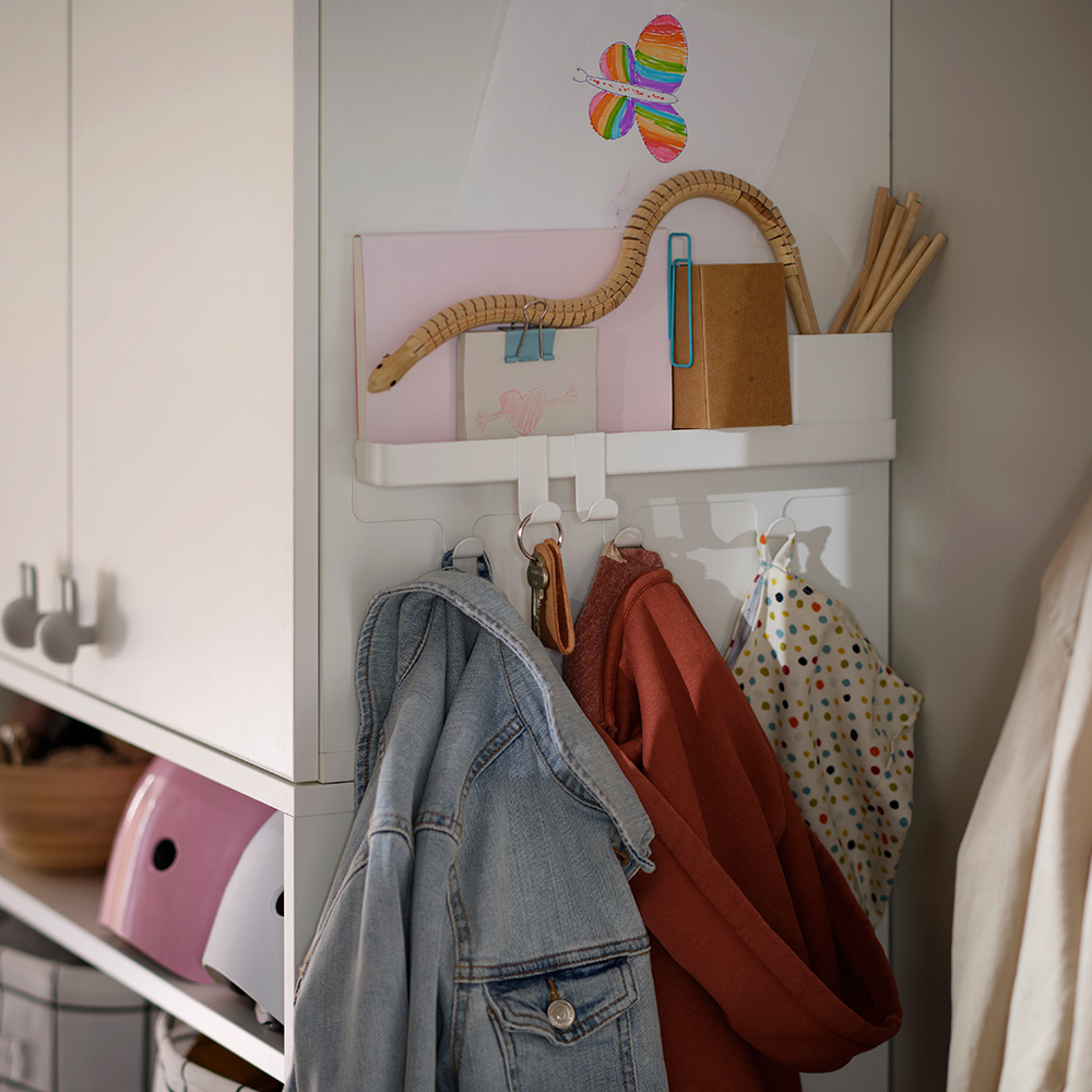 A hallway corner with a ALTARLIDEN hook rack with storage holding jackets, bags and small items on the side of a wardrobe.