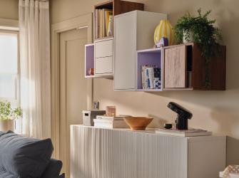 Sala con aparador blanco y módulos de almacenamiento en la pared con libros, plantas y objetos decorativos.