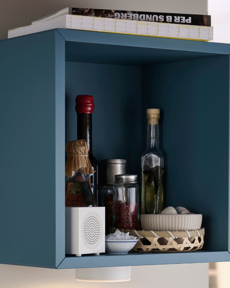 Compact wall storage area with IKEA EKET cabinet, KALLSUP portable speaker, CITRONHAJ salt and pepper set, and KÖLVATTEN LED lights.
