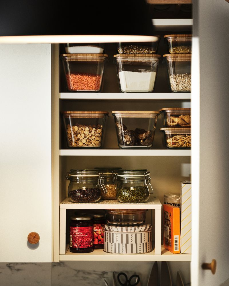 Organized pantry storage with IKEA 365+ containers with lids, KORKEN jar and VARIERA shelf neatly displayed inside cabinet.
