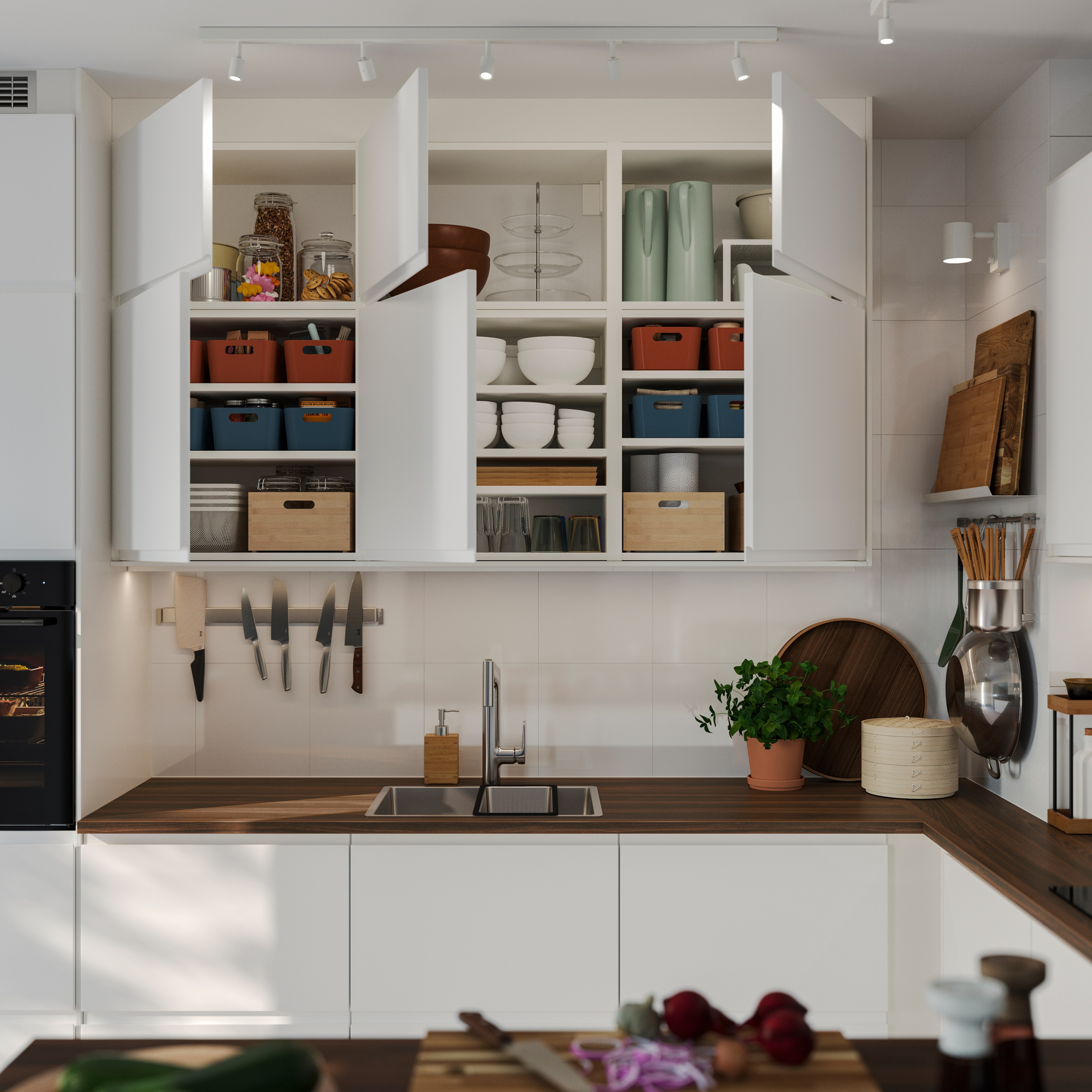 Gabinetes de cocina blancos abiertos con cajas, platos y utensilios organizados sobre la encimera.