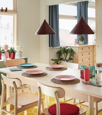 A small wooden breakfast table with two beige chairs against a dark teal wall with matching cabinetry.