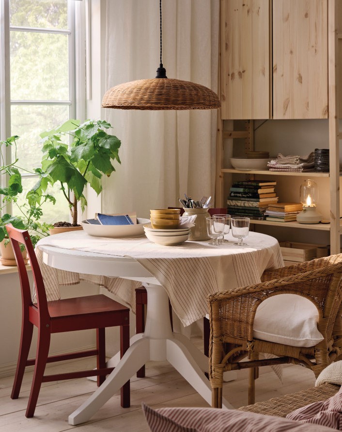 Round table with tableware by a sunlit window.