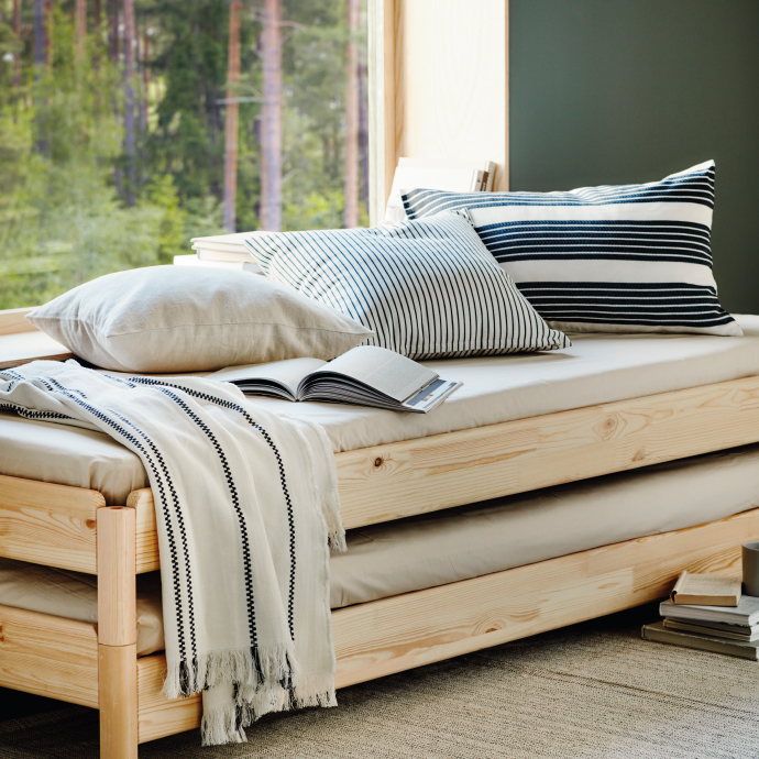 Sofá cama de madera con cojines junto a ventana