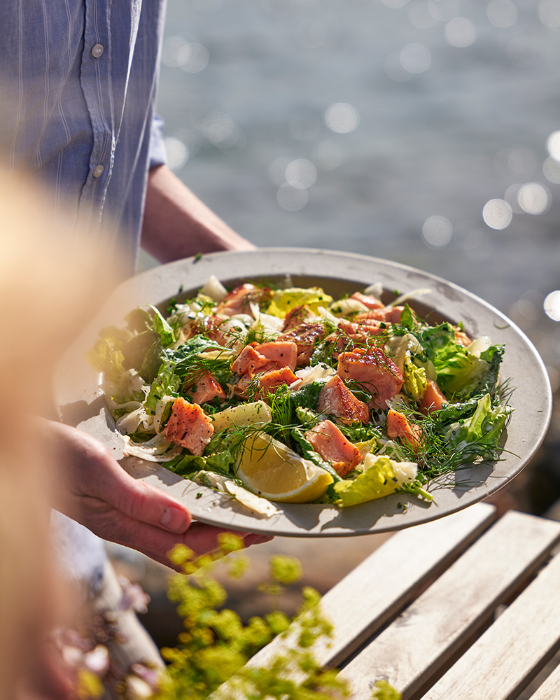 A person holding a STOCKHOLM plate with a dish made from SJÖRAPPORT salmon fillet.