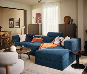 Sala moderna con sofá azul, mesa redonda y decoración cálida.