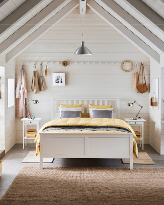 Dormitorio luminoso con cama blanca y textiles en tonos neutros.