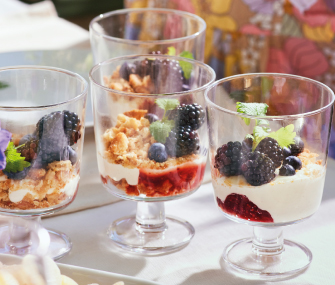 Dessert cups with cream, berries, and granola.
