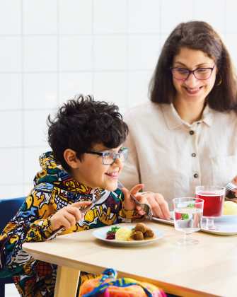 Adult and child eating together at a table.