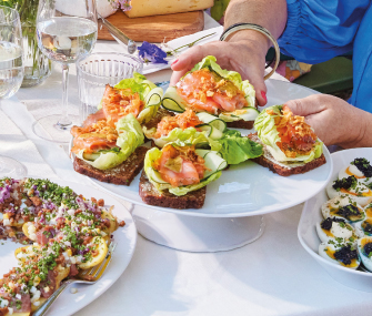 Toasts with salmon, avocado, and salad served on plates.