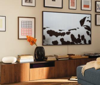 Sala moderna con mueble de madera, cuadros decorativos y sofá azul.