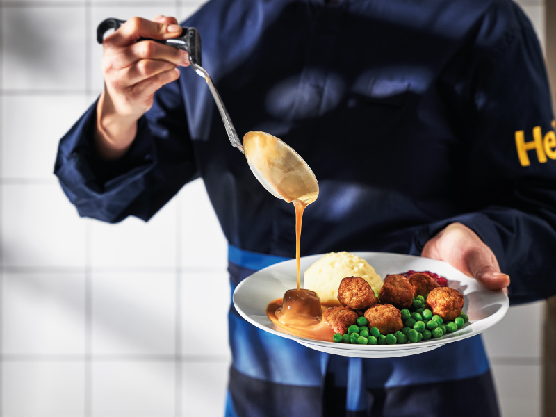 Plate with meatballs, mashed potatoes, and peas topped with gravy.