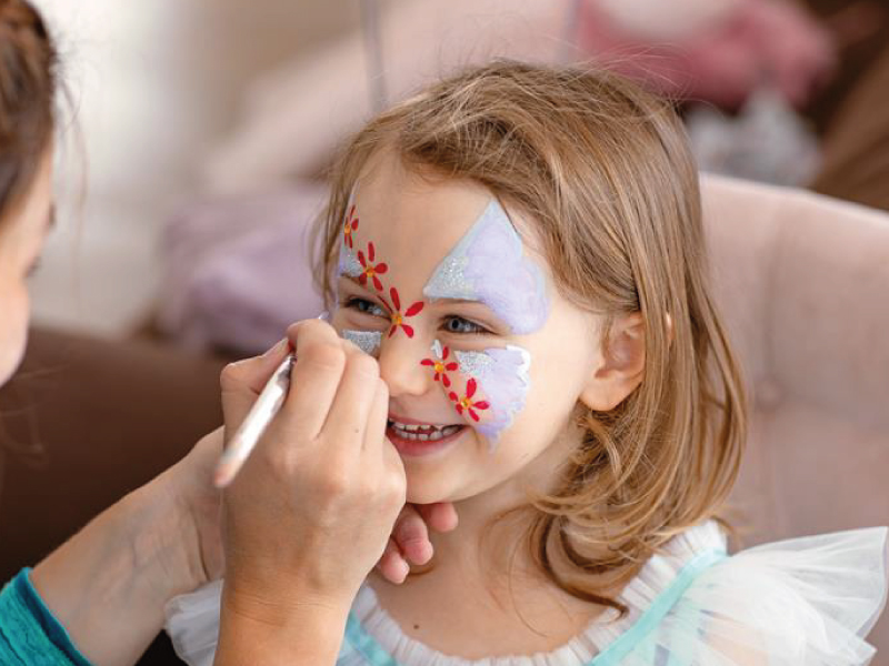 Child getting colorful face painting.