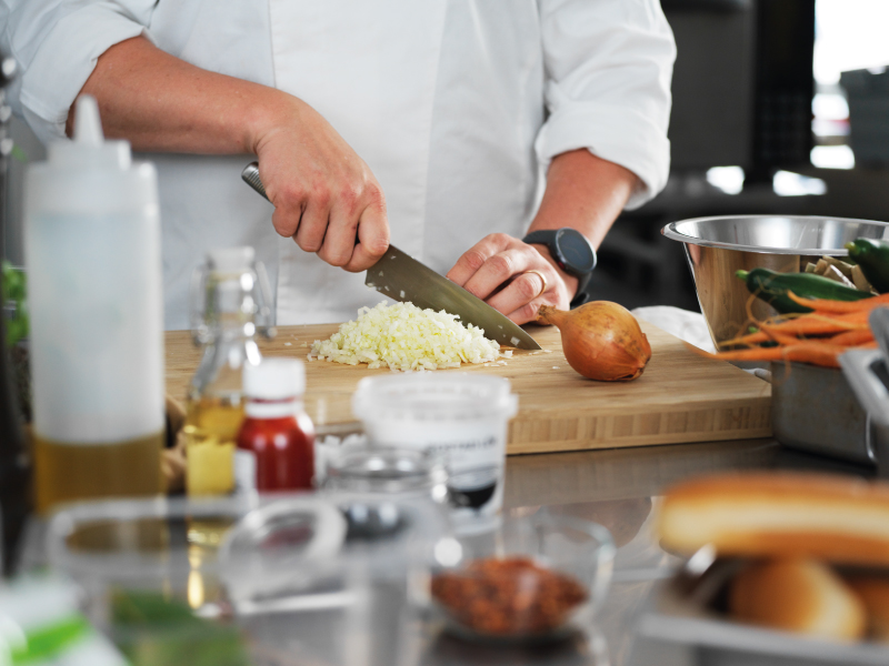 Person chopping an onion on a cutting board in a kitchen.