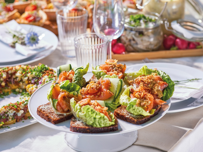 Salmon and lettuce toasts served on an elegant outdoor dining table.