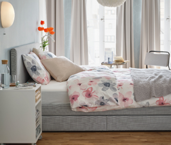 Dormitorio luminoso con cama vestida en ropa de cama floral.
