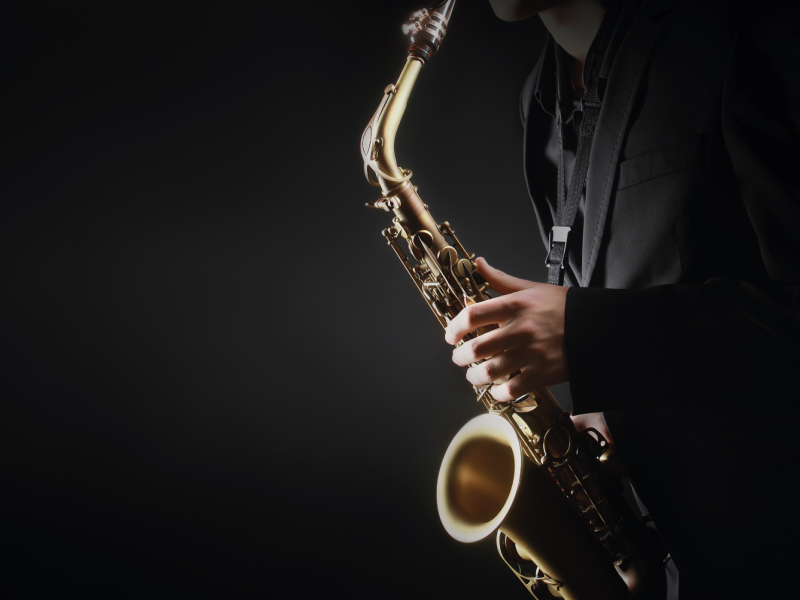 Close-up of a saxophone being played under low lighting.