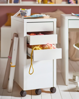 Cajonera blanca con ruedas y materiales de manualidades.
