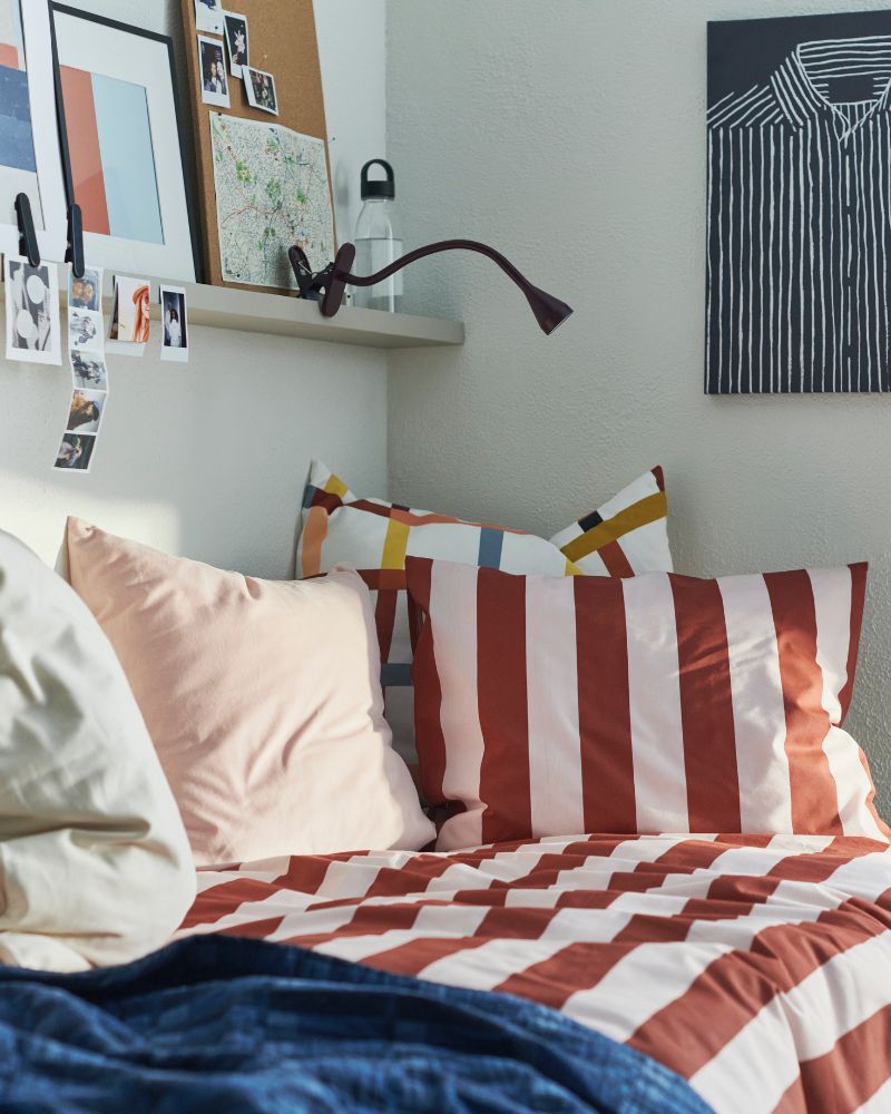 Creative bedroom with SLÅNHÖSTMAL duvet cover set, SKOGSKOVALL bedspread, MOSSLANDA picture ledge and NÄVLINGE spotlight.