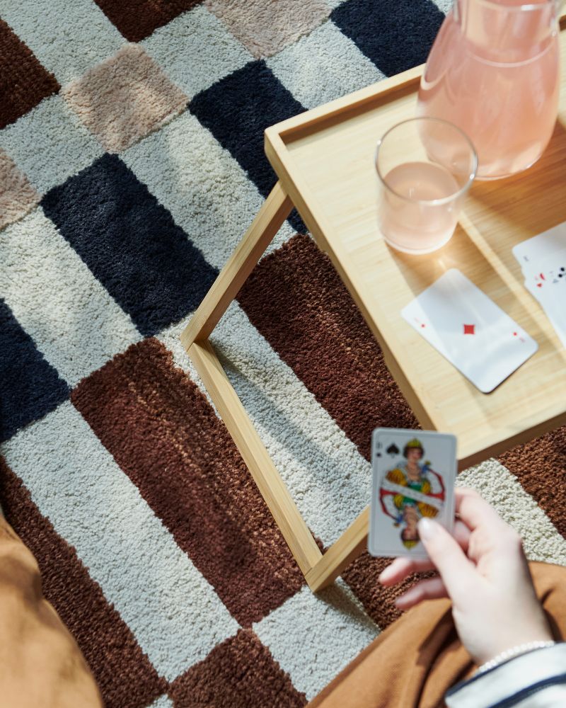Relaxed nook with MARKBLÅMME rug, RESGODS bed tray, KARAFF carafe and STOCKHOLM 2025 glass.