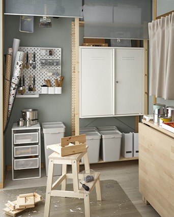 Organized workshop or craft room with shelving units, a pegboard, cabinets, and a wooden step stool.