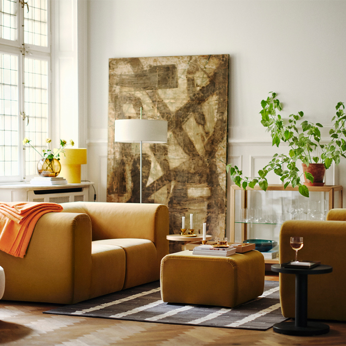Elegant living room with mustard velvet armchairs, a large abstract painting, and indoor plants.