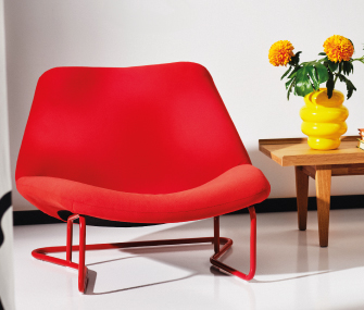 Sillón rojo moderno junto a una mesa de madera con flores amarillas.