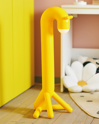 Lámpara infantil amarilla con forma divertida sobre suelo de madera.