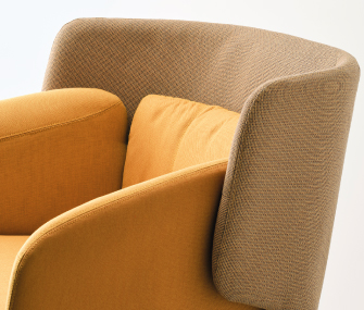 Primer plano de un sillón tapizado en tonos cálidos con cojín de respaldo y diseño envolvente.