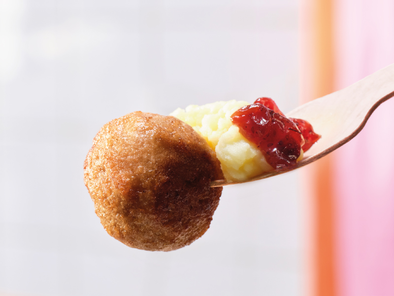 Meatball with mashed potatoes and sauce on a spoon.