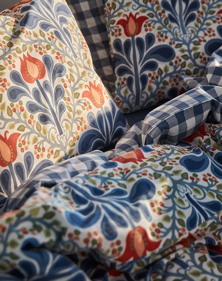 A close-up of the multicoloured SÄTERVIDE duvet cover and pillowcase set with blue and orange flowers.