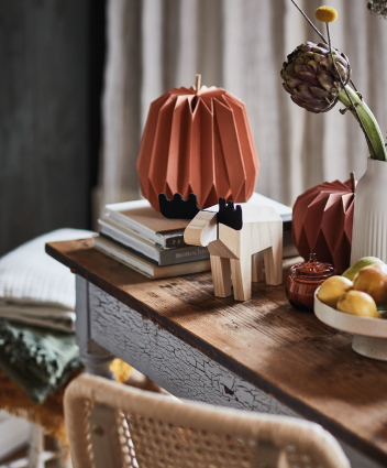 Autumn decor with paper figures, books, and accessories on a wooden console.